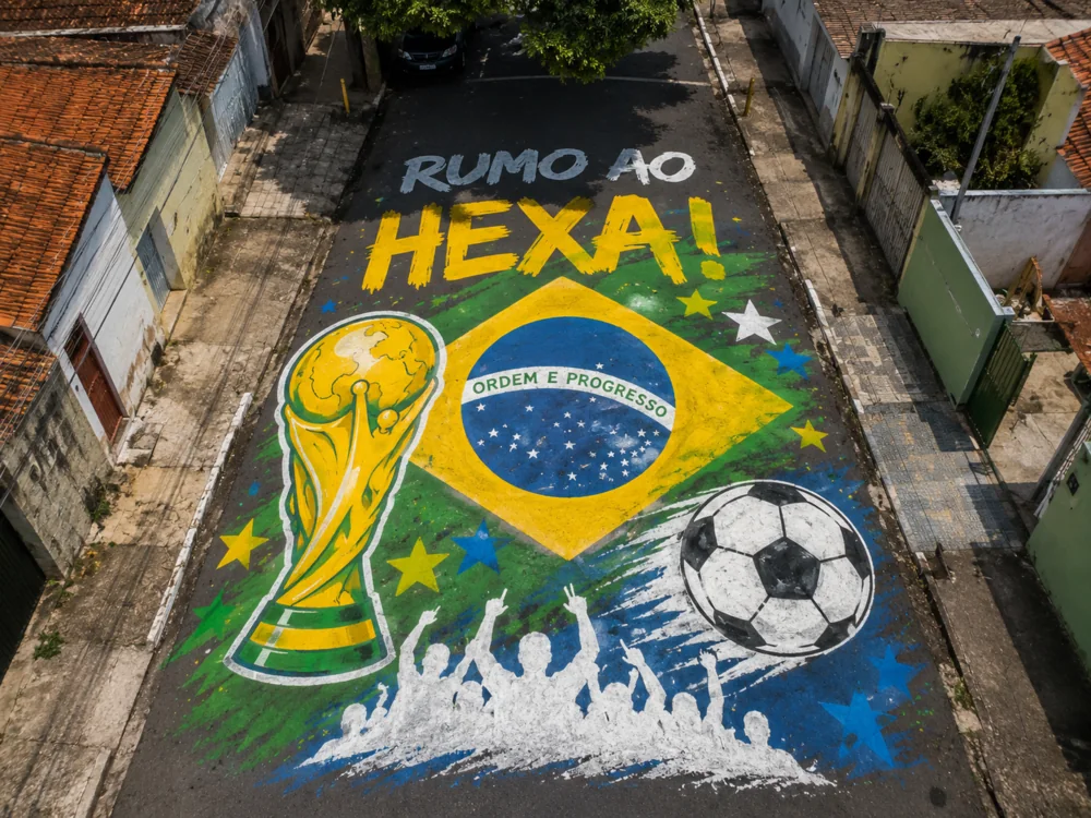 Rua pintada Rumo ao Hexa com a taça da Copa, a bandeira do Brasil e a torcida